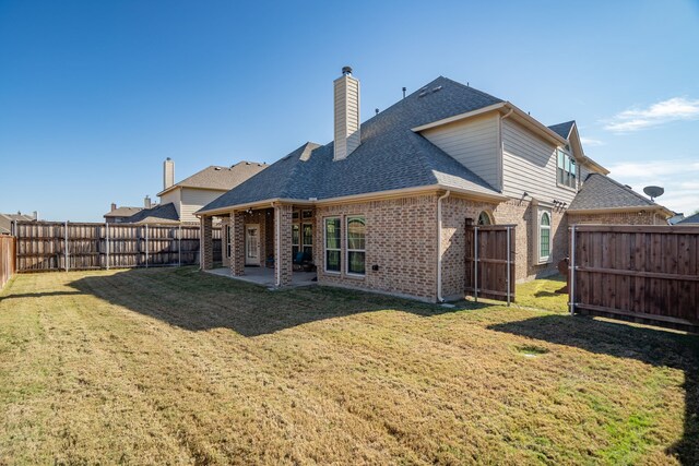 rear view of house with a patio and a lawn