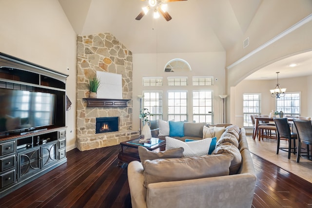 living room with high vaulted ceiling, dark hardwood / wood-style floors, and a stone fireplace