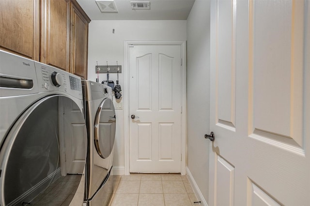 laundry area with cabinets, independent washer and dryer, and light tile patterned floors