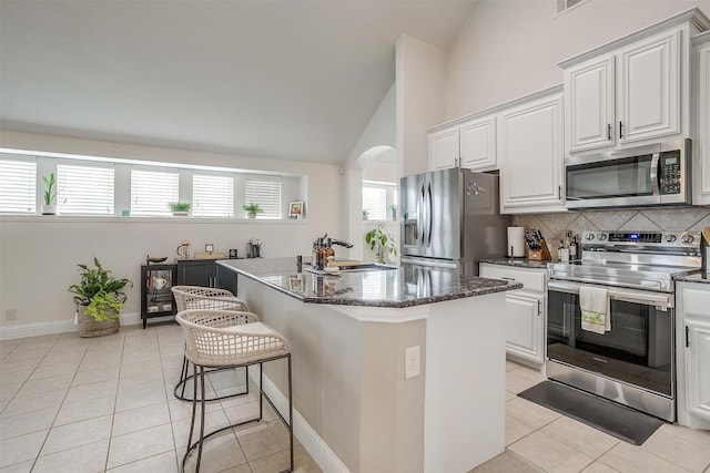 kitchen featuring a center island, sink, stainless steel appliances, light tile patterned flooring, and white cabinets