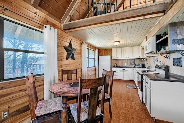 kitchen featuring white cabinetry, plenty of natural light, white appliances, and hardwood / wood-style flooring