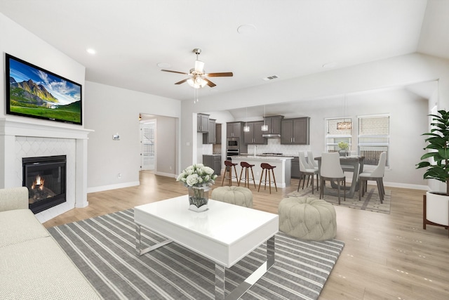 living room featuring ceiling fan, a fireplace, and light hardwood / wood-style flooring