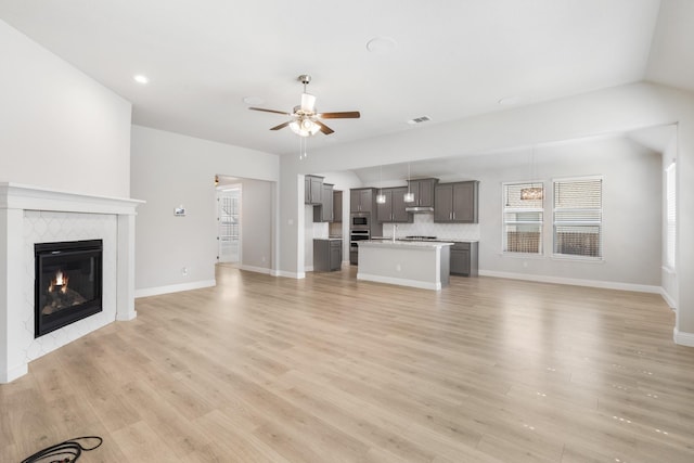 unfurnished living room with ceiling fan, a fireplace, and light hardwood / wood-style flooring