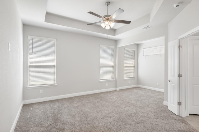 carpeted spare room featuring ceiling fan and a tray ceiling