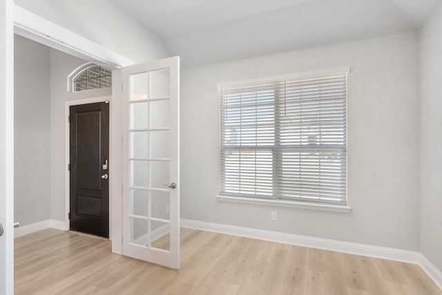 interior space featuring french doors, light wood-type flooring, and vaulted ceiling