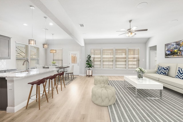 living room with light hardwood / wood-style floors, ceiling fan, and sink