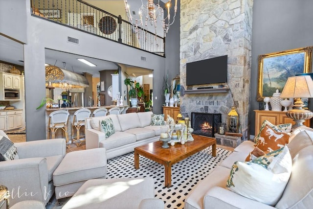 living room with a fireplace, a high ceiling, and a notable chandelier