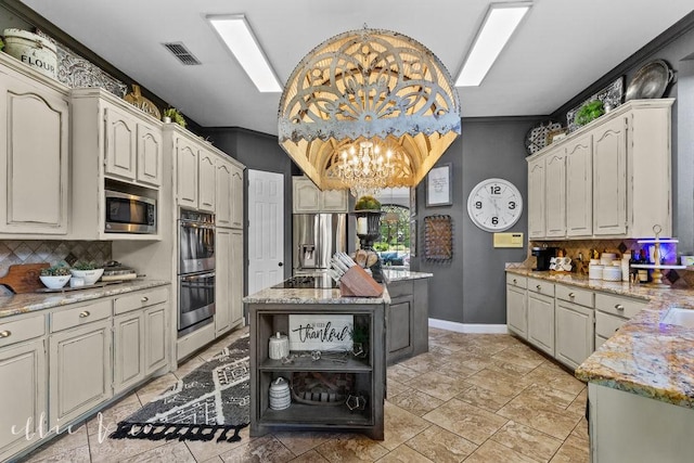 kitchen with backsplash, light stone counters, a kitchen island, and appliances with stainless steel finishes