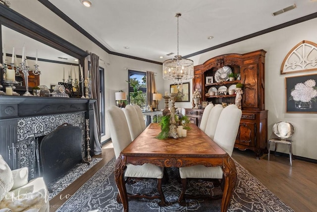 dining area with a tiled fireplace, dark hardwood / wood-style flooring, a notable chandelier, and ornamental molding