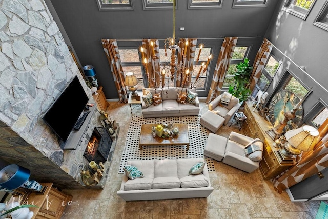 living room with an inviting chandelier and a stone fireplace