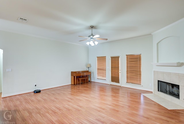 unfurnished living room featuring ceiling fan, light wood-type flooring, ornamental molding, and a fireplace