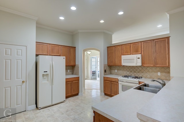 kitchen featuring backsplash, crown molding, sink, and white appliances