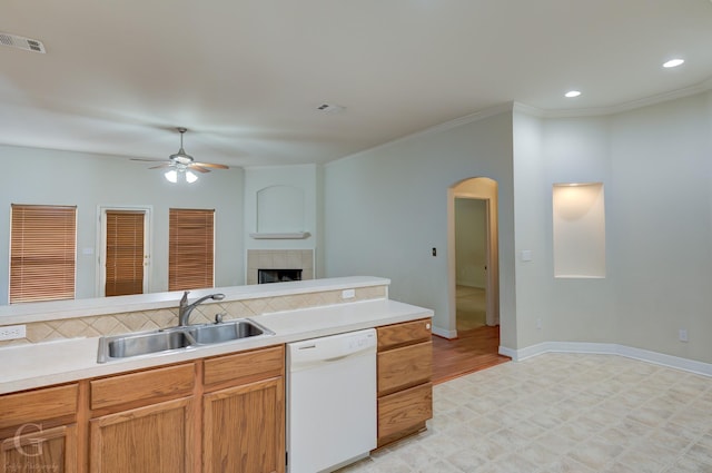 kitchen featuring ornamental molding, ceiling fan, sink, a tile fireplace, and dishwasher