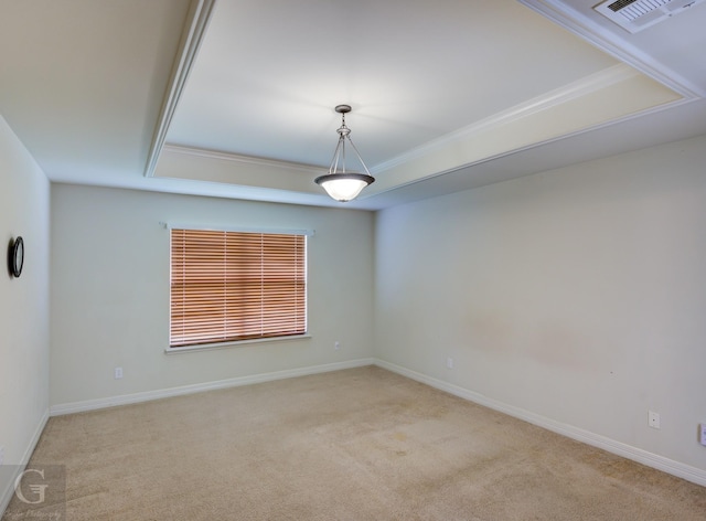 empty room with a raised ceiling, light colored carpet, and crown molding