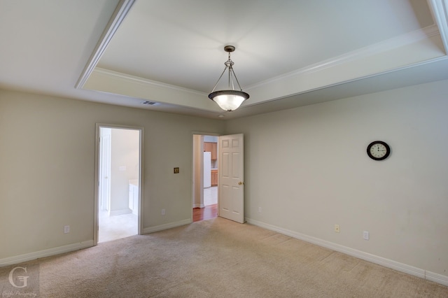 carpeted empty room with crown molding and a tray ceiling