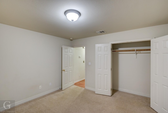 unfurnished bedroom with light carpet and a closet