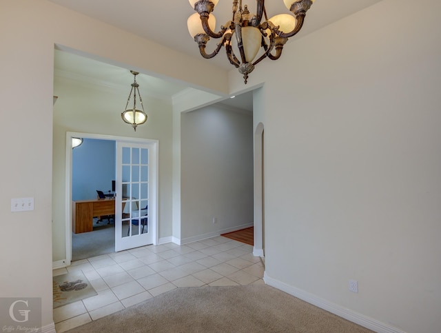 empty room featuring an inviting chandelier, light tile patterned floors, crown molding, and french doors