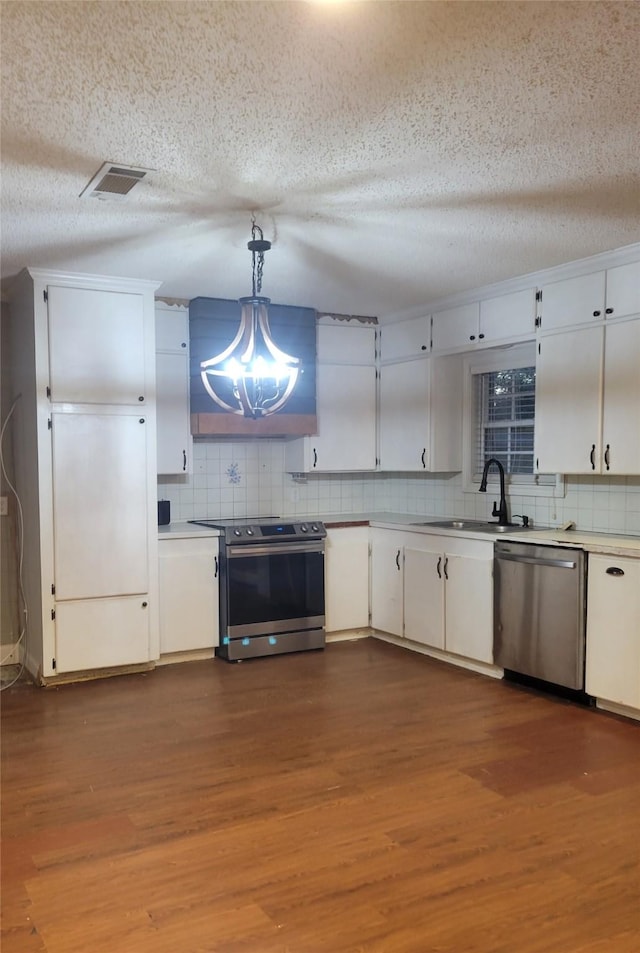 kitchen featuring a textured ceiling, white cabinetry, stainless steel appliances, and hanging light fixtures