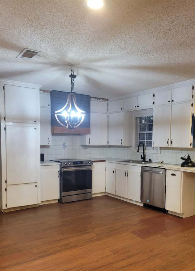 kitchen with a textured ceiling, stainless steel appliances, sink, decorative light fixtures, and white cabinetry