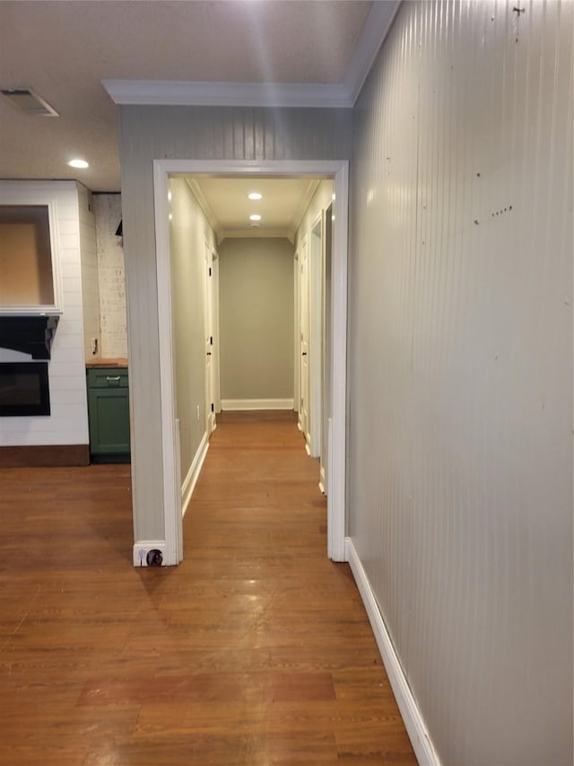 hallway with ornamental molding and light hardwood / wood-style flooring