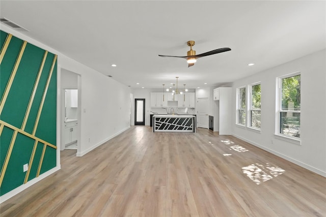 unfurnished living room with ceiling fan, sink, and light hardwood / wood-style flooring