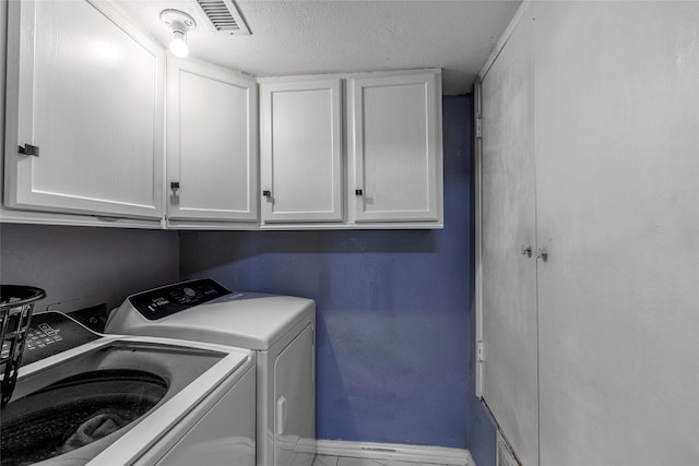 laundry room with cabinets, washing machine and dryer, and a textured ceiling