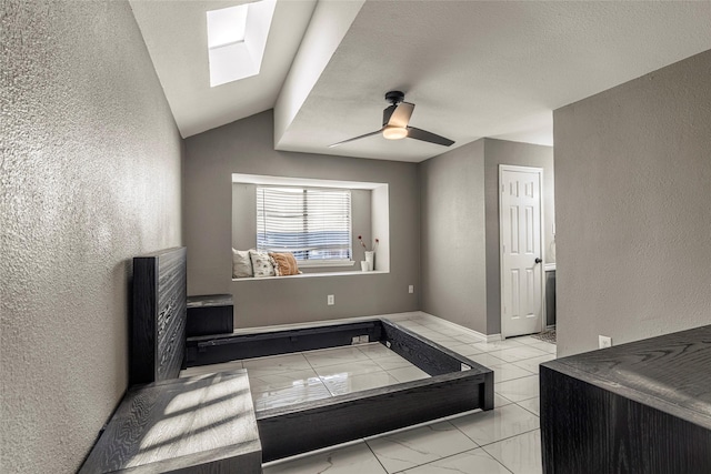 interior space featuring ceiling fan and vaulted ceiling with skylight