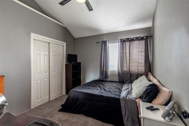 bedroom with lofted ceiling, ceiling fan, carpet floors, a textured ceiling, and a closet