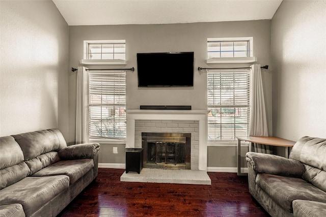 living room featuring dark wood-type flooring and a brick fireplace