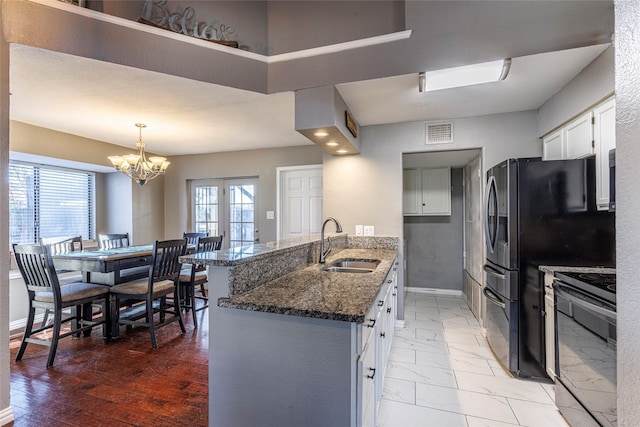 kitchen with sink, white cabinetry, an inviting chandelier, range with electric stovetop, and dark stone counters