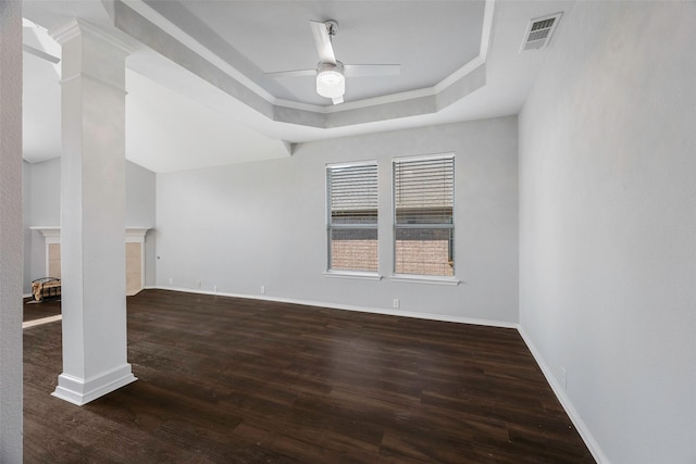 unfurnished living room with dark wood-type flooring, ceiling fan, ornamental molding, a tray ceiling, and decorative columns