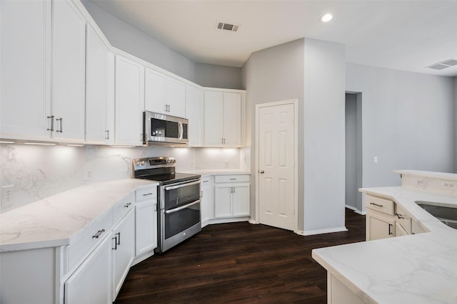 kitchen with white cabinetry, stainless steel appliances, light stone counters, dark hardwood / wood-style floors, and decorative backsplash