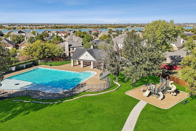 view of swimming pool featuring a lawn, a water view, and a playground