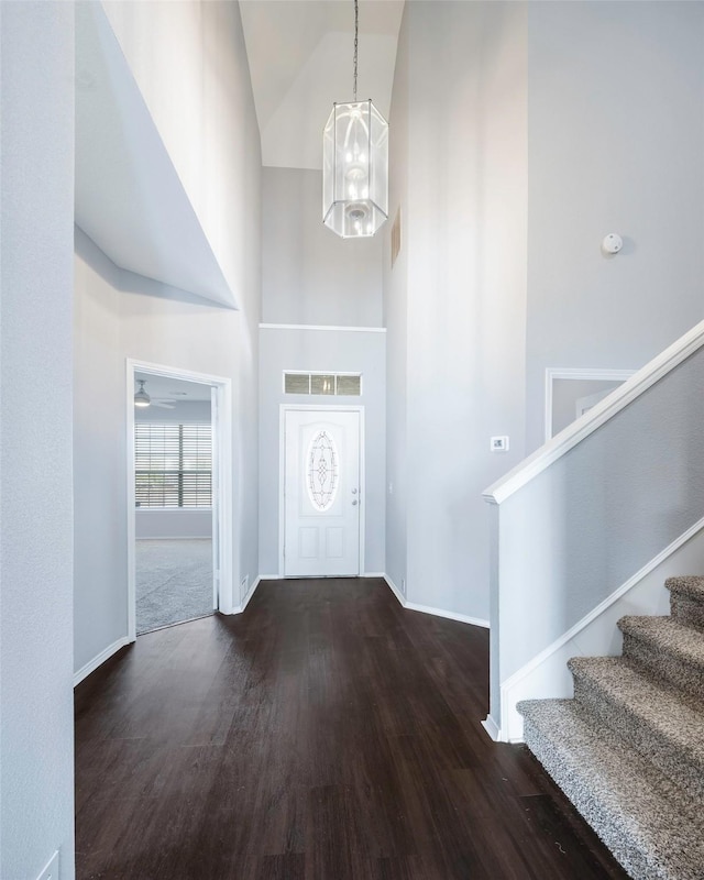 foyer entrance featuring ceiling fan with notable chandelier, dark hardwood / wood-style floors, and high vaulted ceiling