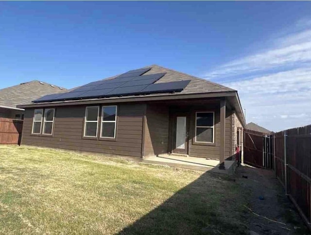 back of property featuring solar panels and a lawn