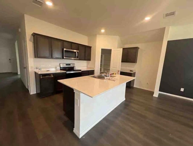 kitchen with dark brown cabinets, stainless steel appliances, a kitchen island with sink, sink, and dark hardwood / wood-style floors