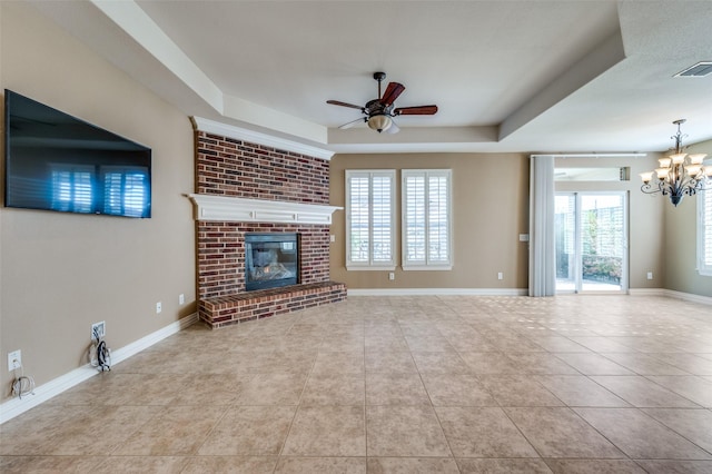 unfurnished living room featuring a brick fireplace, light tile patterned floors, a wealth of natural light, and a tray ceiling