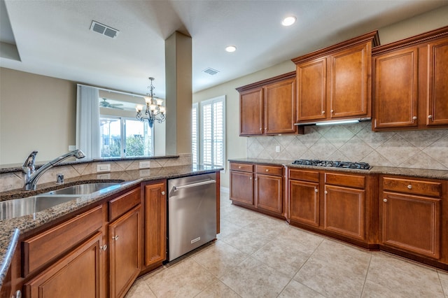 kitchen featuring sink, stainless steel appliances, tasteful backsplash, dark stone countertops, and a chandelier