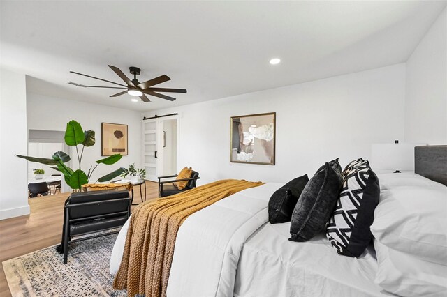 bedroom featuring a barn door, ceiling fan, and hardwood / wood-style floors