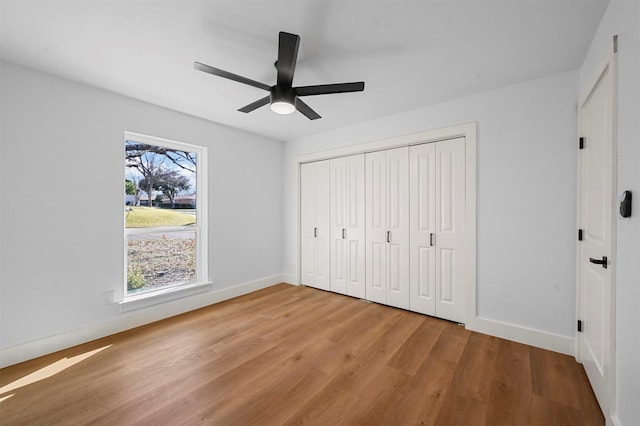 unfurnished bedroom featuring ceiling fan, a closet, and light wood-type flooring