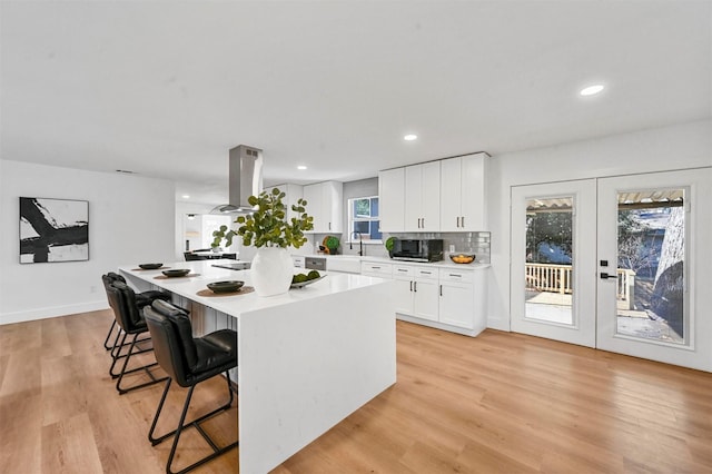 kitchen with decorative backsplash, french doors, white cabinets, a kitchen island, and a breakfast bar area