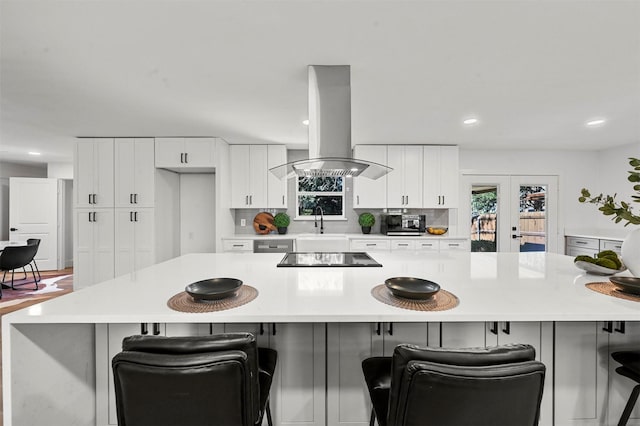 kitchen with island range hood, a kitchen bar, and white cabinetry