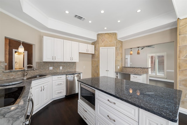 kitchen with white cabinetry, a center island, dark stone counters, and appliances with stainless steel finishes