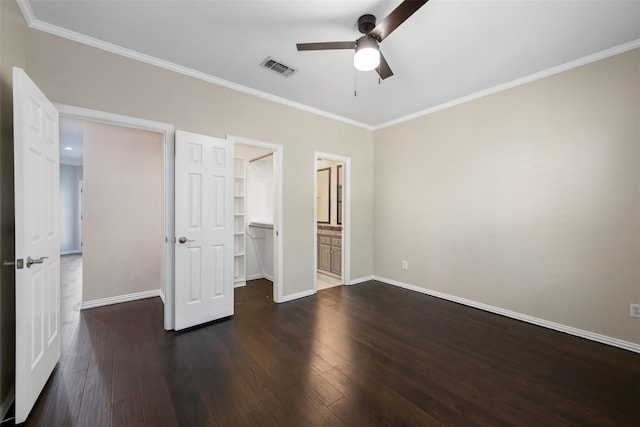 unfurnished bedroom with ornamental molding, a walk in closet, ceiling fan, dark wood-type flooring, and a closet