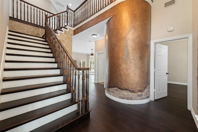 stairway with hardwood / wood-style flooring, a towering ceiling, and ceiling fan