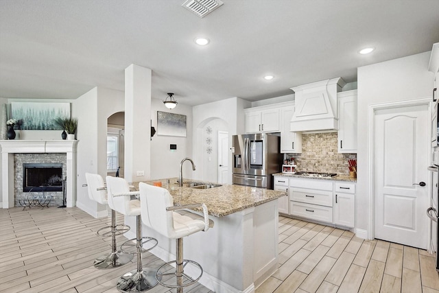 kitchen featuring white cabinetry, premium range hood, sink, and appliances with stainless steel finishes