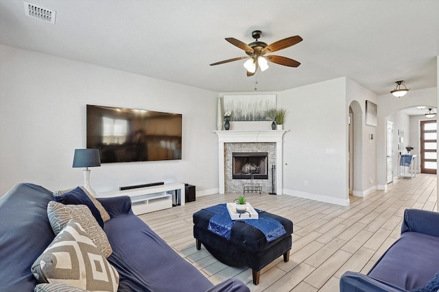 living room with ceiling fan and a fireplace