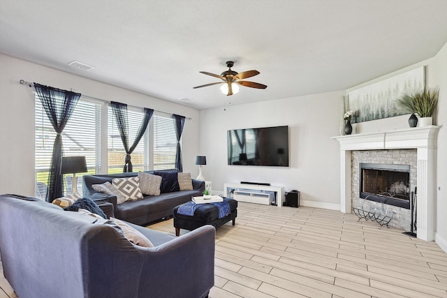 living room with ceiling fan, a brick fireplace, and light wood-type flooring