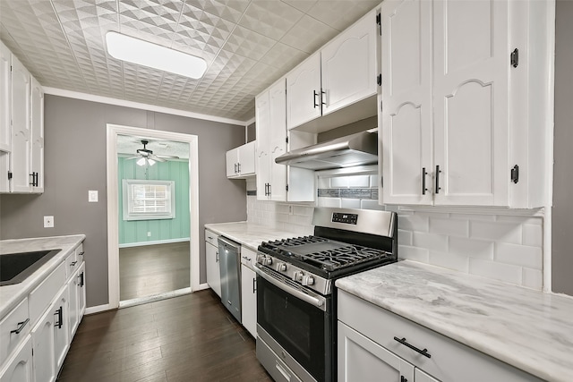 kitchen with crown molding, ceiling fan, range hood, appliances with stainless steel finishes, and white cabinetry