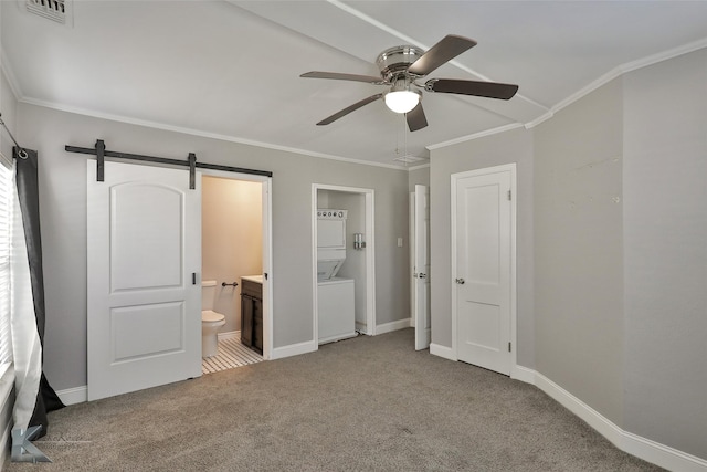 unfurnished bedroom with ensuite bath, ceiling fan, a barn door, crown molding, and carpet